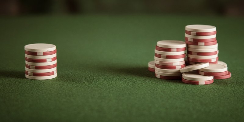 A small stack of poker chips set apart from a larger group on green felt.