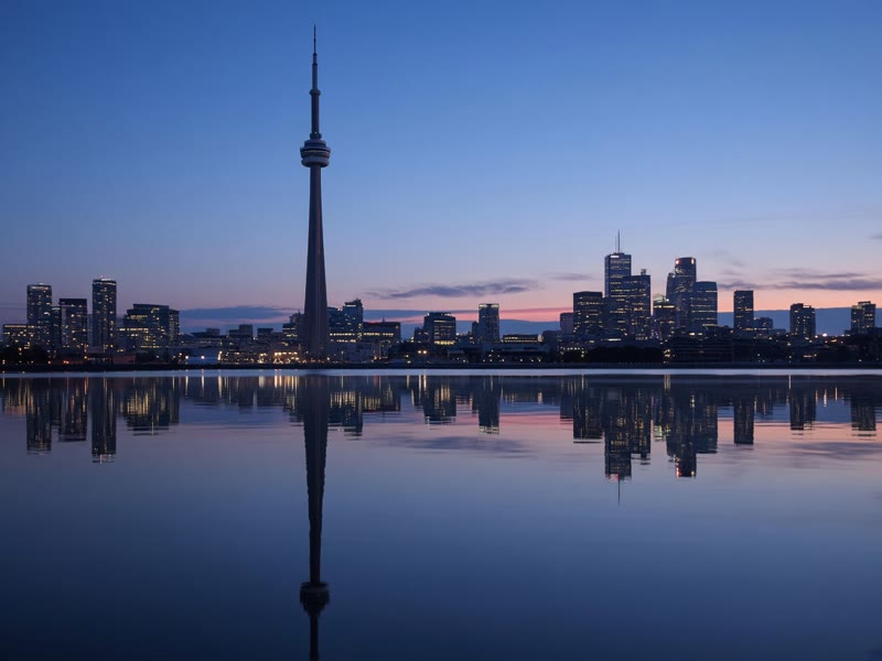 The CN Tower reflected in Lake Ontario at dusk.
