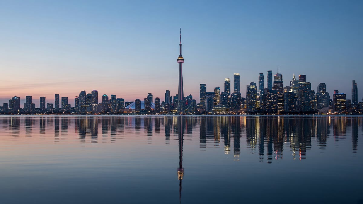 The Toronto skyline and CN Tower at dusk, seen across Lake Ontario.