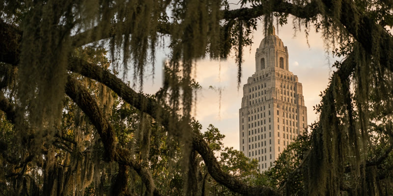 The Louisiana State Capitol tower framed by moss-hung live oaks in Baton Rouge.