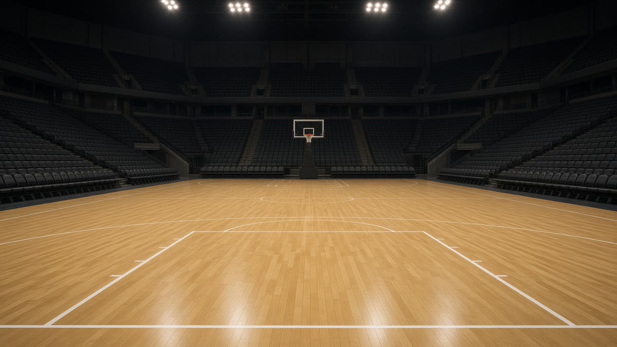 Eine leere Basketballarena unter hellem Licht mit Parkettboden.