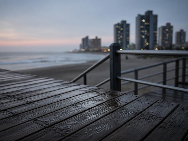 Wet boardwalk planks beside the beach in Atlantic City at dusk.