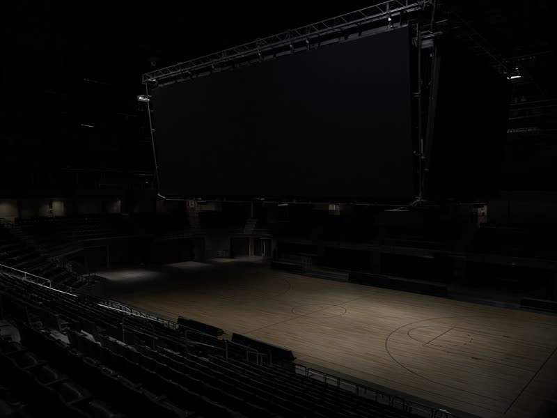 A dark arena scoreboard above an empty basketball court.